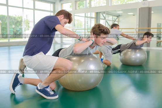 Two men being held in position on aerobic balls. Стоковое фото, агентство Ingram Publishing / Фотобанк Лори