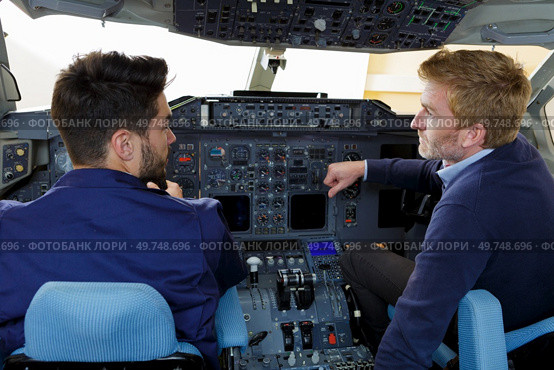 two pilots dressed in uniform flying jet airliner. Стоковое фото, агентство Ingram Publishing / Фотобанк Лори