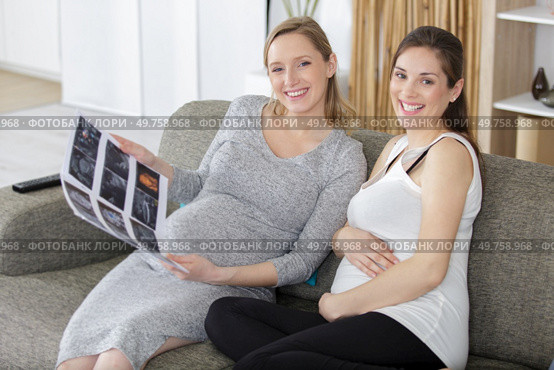 two pregnant women sitting on sofa. Стоковое фото, агентство Ingram Publishing / Фотобанк Лори