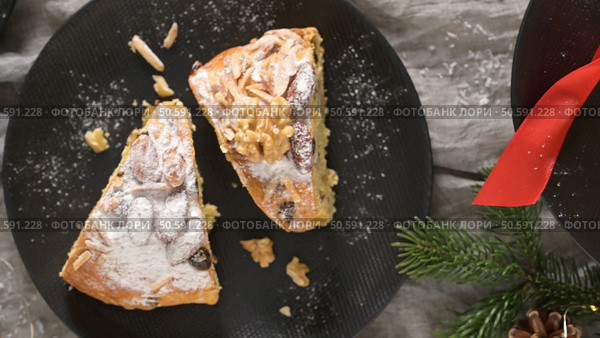 Two slices of Bolo Rainha cake dusted with powdered sugar and topped with nuts on a black plate Festive holiday vibes. Стоковое фото, агентство Ingram Publishing / Фотобанк Лори