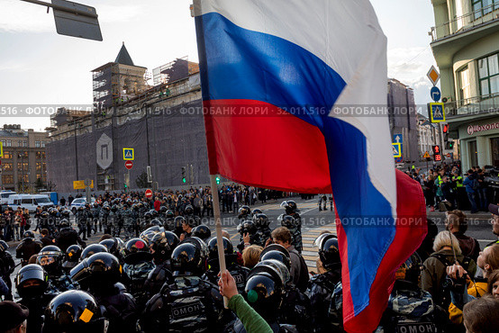 Участник несанкционированной властями оппозиционной акции держит российский флаг на улице Маросейка города Москвы, Россия, 10 августа 2019. Редакционное фото, фотограф Николай Винокуров / Фотобанк Лори