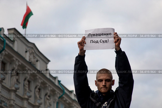 Участник пикета против Президента РБ Александр Лукашенко на акциях протеста оппозиции в Белоруссии у посольства Республики Беларусь на улице Маросейке в городе Москве держит плакат с надписью "Лукашенко под суд!", Россия (2020 год). Редакционное фото, фотограф Николай Винокуров / Фотобанк Лори