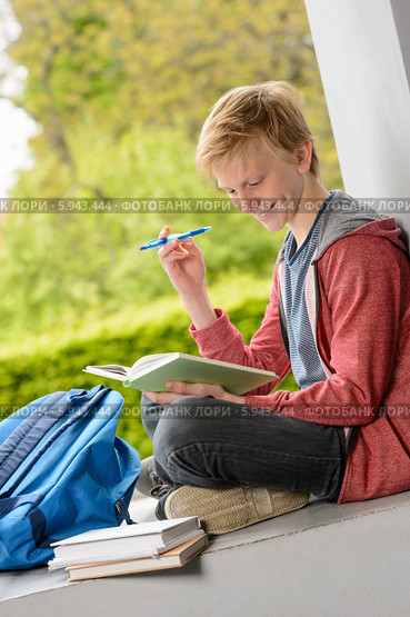 Улыбающийся первокурсник читает книгу, сидя на полу. Стоковое фото, фотограф CandyBox Images / Фотобанк Лори