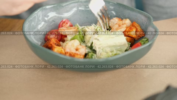 Unrecognized Male Person Eat Caesar Salad with Shrimps, Lettuce, Tomatoes, Croutons. Young Man Eating Fresh Vegetable Delicious Side Dish in a Restaurant. Business Lunch. Healthy food. Vegetarian food. Стоковое видео, видеограф Марина Демидюк / Фотобанк Лори