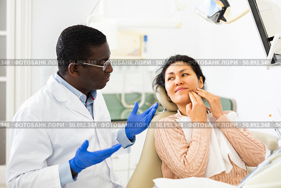 Upset Asian woman complaining to dentist about toothache. Стоковое фото, фотограф Яков Филимонов / Фотобанк Лори