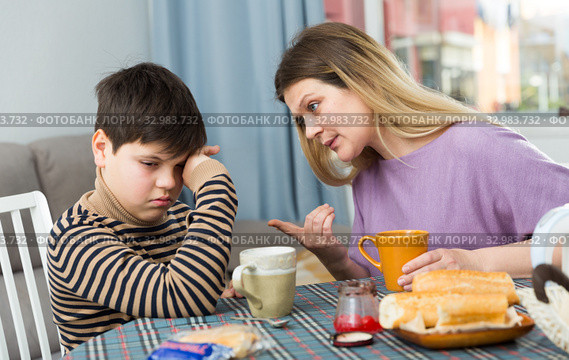 Upset mother and unhappy son arguing during breakfast indoors. Стоковое фото, фотограф Яков Филимонов / Фотобанк Лори