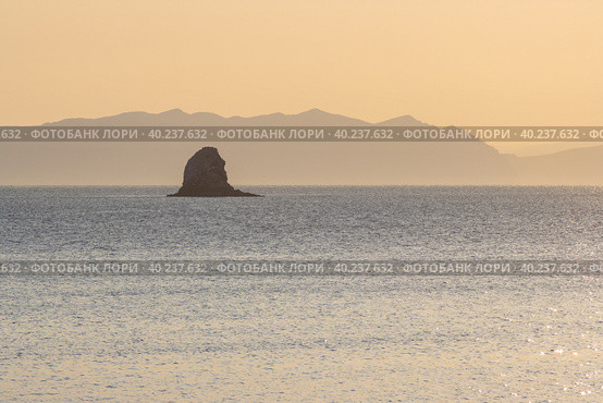 Утренний морской пейзаж. Вид на морской залив и скалу в море. Горы вдалеке. Золотистый солнечный свет на рассвете. Бухта Гертнера, Охотское море, Магаданская область, Дальний Восток России. Стоковое фото, фотограф Андрей Степанов / Фотобанк Лори