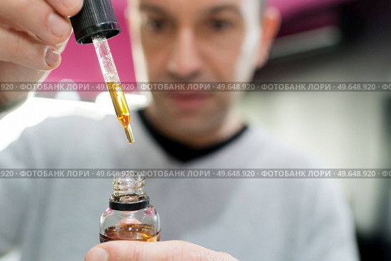 vape shop seller filling liquid in e-cigarette. Стоковое фото, агентство Ingram Publishing / Фотобанк Лори