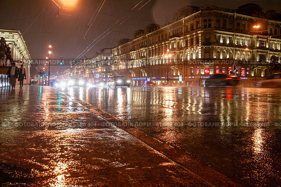 Вечерний Санкт-Петербург, Россия. Вид на Аничков мости и Невский проспект во время дождя. По улице едут автомобили. По тротуару идут пешеходы с зонтом. Исторический центр Санкт-Петербурга. Дождливая погода. Осень. Редакционное фото, фотограф Андрей Степанов / Фотобанк Лори