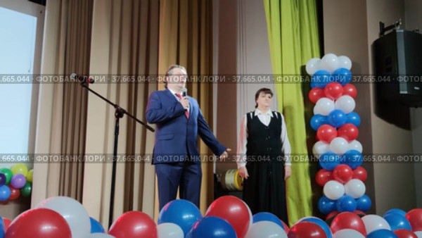 Ведущие проводят праздничное мероприятие на сцене дома культуры. The presenters hold a festive event on the stage of the House of culture. Редакционное видео, видеограф Мария / Фотобанк Лори