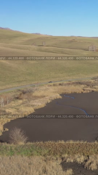 Vertical drone video of flying over a hilly rural landscape with a winding road and fish ponds. Altai Krai. Стоковое видео, видеограф Сергей Пристяжнюк (Serg Zastavkin) / Фотобанк Лори