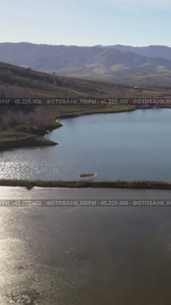 Vertical drone video of flying over a hilly rural landscape with a winding road and fish ponds. Altai Krai. Стоковое видео, видеограф Сергей Пристяжнюк (Serg Zastavkin) / Фотобанк Лори