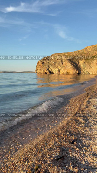 Vertical video of beautiful Baikal Lake at sunset light. Olkhon Island. Deserted sandy beach with steep cliffs along shore of Small Sea with blue pure transparent water in July evening. Natural background. Стоковое видео, видеограф Виктория Катьянова / Фотобанк Лори