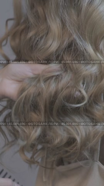 Vertical video of woman stylist combing long wavy blond female hair from back side. Стоковое видео, видеограф Сергей Пристяжнюк (Serg Zastavkin) / Фотобанк Лори