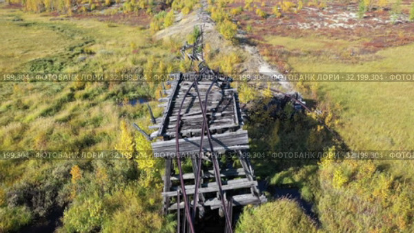 Вид осенью на старый железнодорожный мост железной дороги "Чум - Салехард - Игарка" сталинской 501-й стройки ГУЛАГ. Ямало-Ненецкий автономный округ. Стоковое видео, видеограф Григорий Писоцкий / Фотобанк Лори