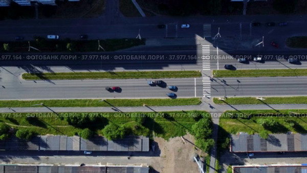 Вид с воздуха на регулируемый светофором пешеходный переход через оживленное городское шоссе. Машины останавливаются пропуская пешеходов. Боковое движение камеры (2022 год). Стоковое видео, видеограф Sergei Gorin / Фотобанк Лори
