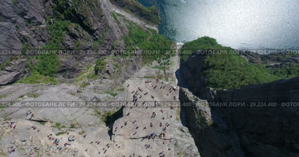 Вид сверху и подъем камеры. Скала Кафедра проповедника (Preikestolen), туристы на плато. Гигантский утёс над Люсе-фьордом, Форсанн, Норвегия (2018 год). Стоковое видео, видеограф Кекяляйнен Андрей / Фотобанк Лори