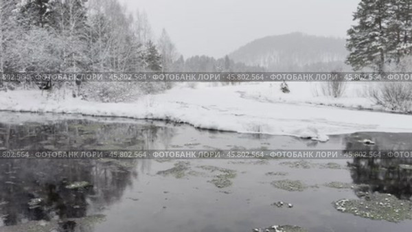 Video of a winter landscape with the non-freezing Oda River into which natural springs and sources flow. Snow-covered riverbank and fields and forest in the distance. Winter travel and walks during the New Year holidays. Стоковое видео, видеограф Виктория Катьянова / Фотобанк Лори