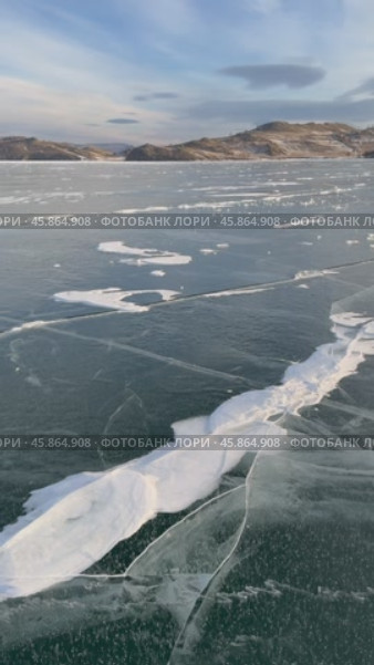Video of Baikal Lake in December. Panoramic view of blue clear ice with snowy cracks of frozen Kurkut Bay of Small Sea Strait at sunset. Beautiful winter landscape. Nature background. Winter travels. Стоковое видео, видеограф Виктория Катьянова / Фотобанк Лори