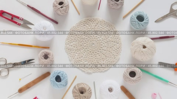 Video of needlework and crochet supplies lying around beautiful hand crocheted lace doily on white background. DIY concept. Crocheting as a hobby. Flat lay, close-up, mock up. Стоковое видео, видеограф Виктория Катьянова / Фотобанк Лори