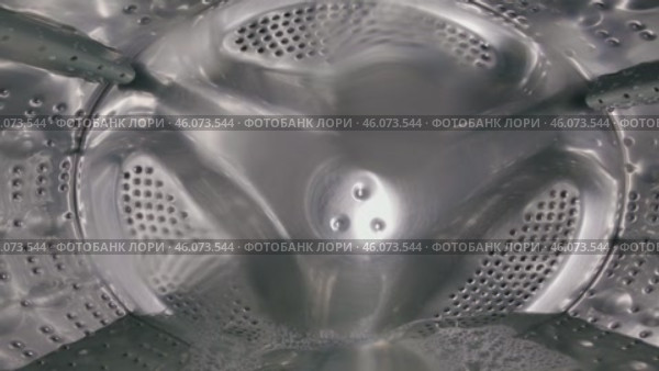 View from inside the drum of a washing machine with perforated holes, centre agitator and water during operation. Time-lapse. Close-up. Стоковое видео, видеограф Воловодов Владимир / Фотобанк Лори