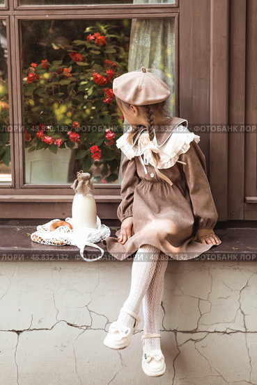 Vintage accessories and retro-style clothes. A small, beautiful girl with bows in her hair, in a beige dress and a beret outdoors with bagels and milk in a string bag. Стоковое фото, фотограф Photojuli / Фотобанк Лори