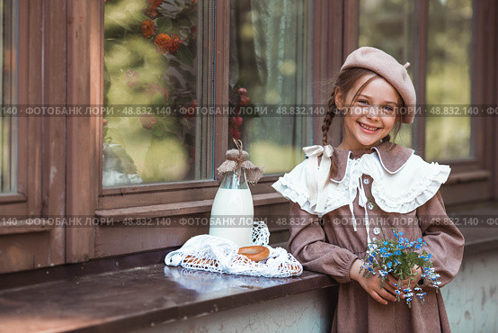 Vintage accessories and retro-style clothes. A small, beautiful girl with bows in her hair, in a beige dress and a beret outdoors with bagels and milk in a string bag. Стоковое фото, фотограф Photojuli / Фотобанк Лори