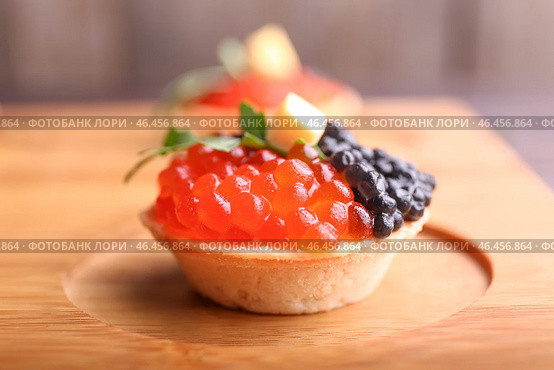 Вкусная корзиночка с икрой на деревянной доске, крупным планом. Стоковое фото, фотограф Pixel_shot / Фотобанк Лори