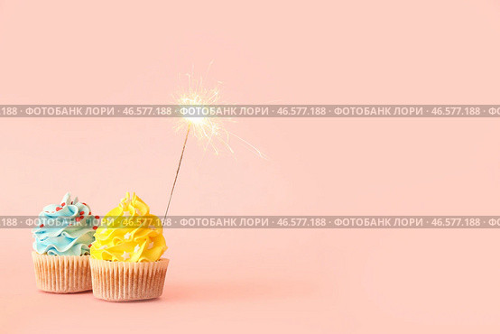 Вкусные день рождения кексы с бенгальской зажигалкой на розовом фоне. Стоковое фото, фотограф Pixel_shot / Фотобанк Лори