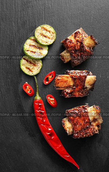 Вкусные говяжьи ребрышки с овощами на темном фоне. Стоковое фото, фотограф Pixel_shot / Фотобанк Лори