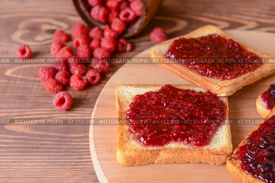 Вкусный поджаренный хлеб и малиновое варенье на деревянной доске. Стоковое фото, фотограф Pixel_shot / Фотобанк Лори