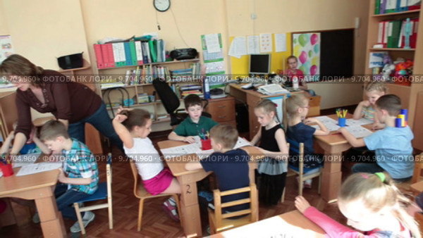 Воспитатель раздает цветные карандаши детям перед началом урока в детском садике (2015 год). Редакционное видео, видеограф Кекяляйнен Андрей / Фотобанк Лори