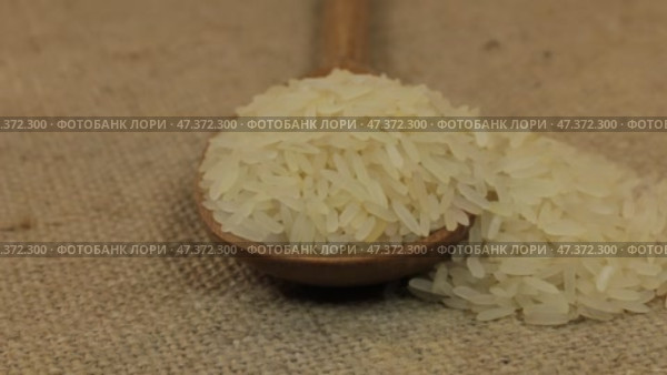 Вращающаяся ложка, наполненная рисовыми зернами, лежащими на мешковине. Крупный план. Стоковое видео, видеограф Александр Собко / Фотобанк Лори