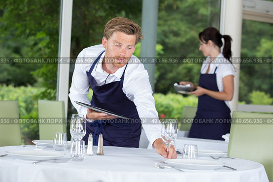 waiter setting formal dinner table. Стоковое фото, агентство Ingram Publishing / Фотобанк Лори