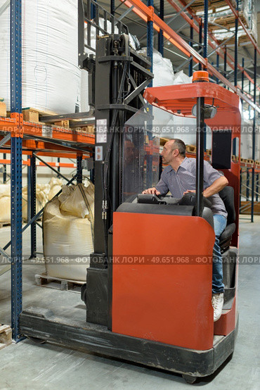 warehouse worker using fork truck to load pallet on racking. Стоковое фото, агентство Ingram Publishing / Фотобанк Лори