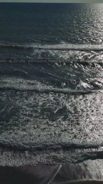Warm sunlight glimmering across rippling ocean surface, gentle waves lapping sandy shoreline, embodying tranquil coastal serenity. Стоковое видео, видеограф ILIA GOROKHOV / Фотобанк Лори