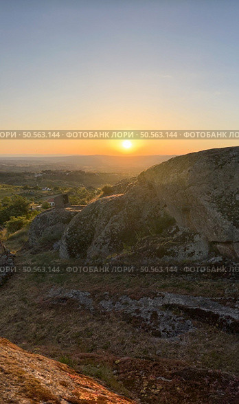 Warm sunset glow bathes rugged terrain, offering a serene expansive view. Guarda - Portugal. Стоковое фото, агентство Ingram Publishing / Фотобанк Лори