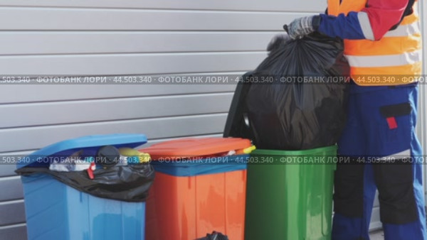 Waste collection worker sorts trash at local facility in vibrant recycling bins during mid-afternoon shift. Стоковое видео, видеограф Сергей Толмачёв / Фотобанк Лори