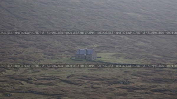 Weathered stone cottage perched on misty Scottish hillside, stone wall enclosing rustic dwelling against rolling green landscape, evoking serene rural charm. Стоковое AI-видео, аниматор Данил Руденко / Фотобанк Лори
