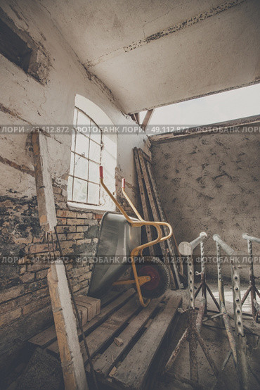 Wheelbarrow in a warn barn with sunlight coming through a window. Стоковое фото, агентство Ingram Publishing / Фотобанк Лори