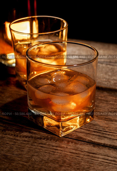 Whiskey, bourbon or brown rum with ice on wood table. Whiskey or bourbon. Стоковое фото, агентство Ingram Publishing / Фотобанк Лори