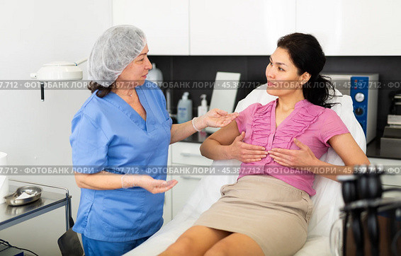 Woman asking cosmetologist about breast lift and reshaping procedures. Стоковое фото, фотограф Яков Филимонов / Фотобанк Лори