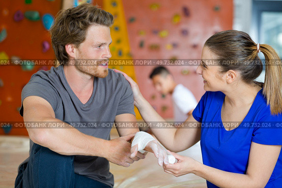 woman bandaging injured hand of a sportman. Стоковое фото, агентство Ingram Publishing / Фотобанк Лори