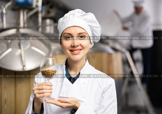 Woman brewer holding glass with malted grain in brewery. Стоковое фото, фотограф Яков Филимонов / Фотобанк Лори