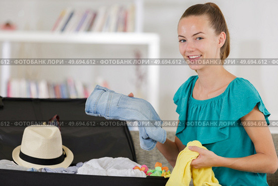 woman choosing things to pack into suitcase. Стоковое фото, агентство Ingram Publishing / Фотобанк Лори