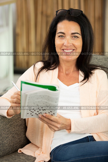 woman doing crosswords sitting on couch. Стоковое фото, агентство Ingram Publishing / Фотобанк Лори