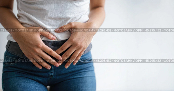 Woman grips lower stomach, indicating discomfort, likely from premenstrual syndrome. suffer from PMS premenstrual. White background, copy space. Стоковое фото, фотограф Павел Муравьев / Фотобанк Лори