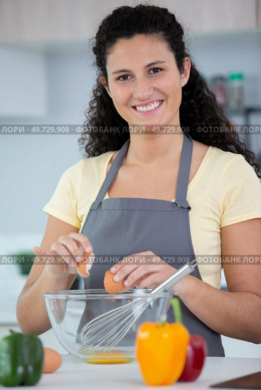 woman in kitchen cracking egg intoa bowl. Стоковое фото, агентство Ingram Publishing / Фотобанк Лори