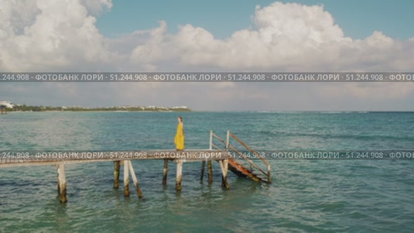 Woman in summer dress walks on old wooden pier above calm sea in Yucatan Mexico. Стоковое видео, видеограф Ольга Сухарева / Фотобанк Лори