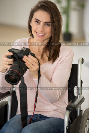 woman in wheelchair at home holding dslr camera. Стоковое фото, агентство Ingram Publishing / Фотобанк Лори